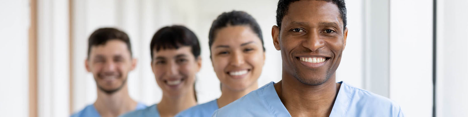 A group of four men and women wearing blue scrubs standing in a staggered line