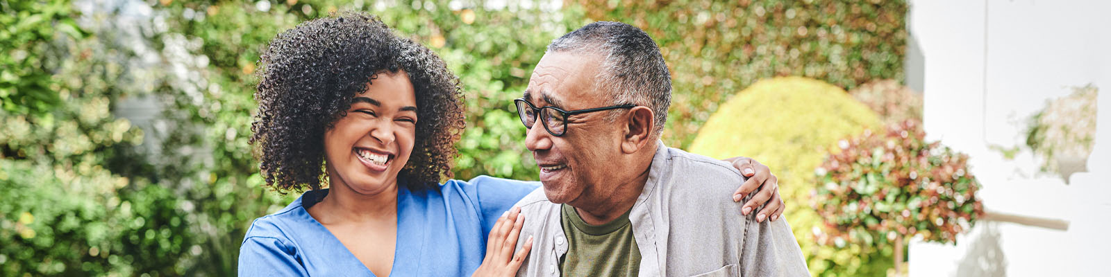 A senior man walking outdoors with his nursing assistant