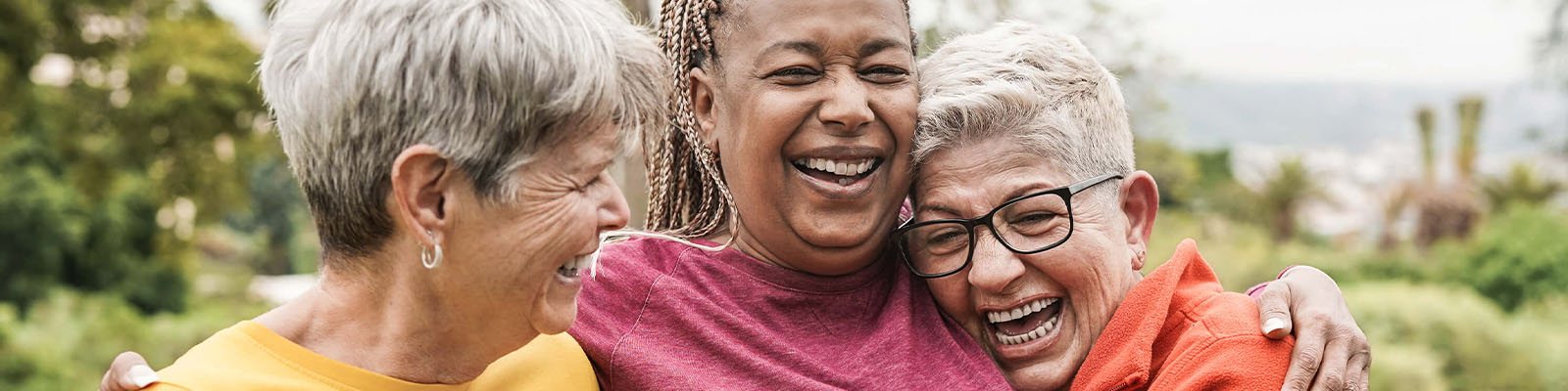 Three senior women standing together and smiling while laughing